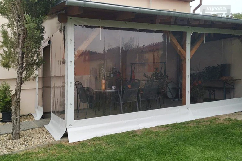 Pergola s plachtou na zahradě obklopující jídelní stůl.