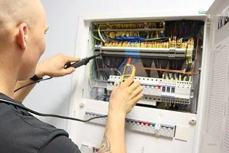 Elektrikář měří napětí v rozvaděči pomocí multimetru.