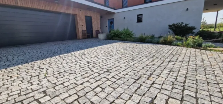 Překrytá zámková dlažba na svažitém terénu před domem.