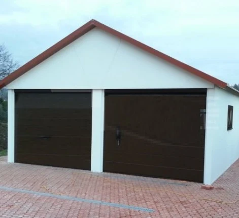 Bílá omítnutá plechová garáž s dvěma bránami na dlažbě.