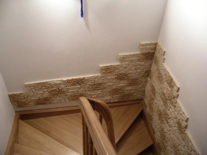Detail dřevěného schodiště s kamennou úpravou stěn.