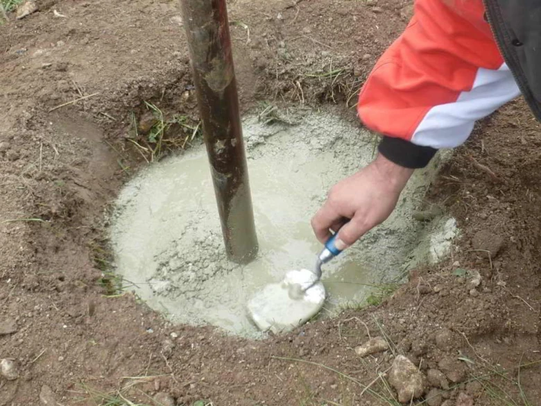 Lidá se beton do jámy kolem sloupu při stavbě.