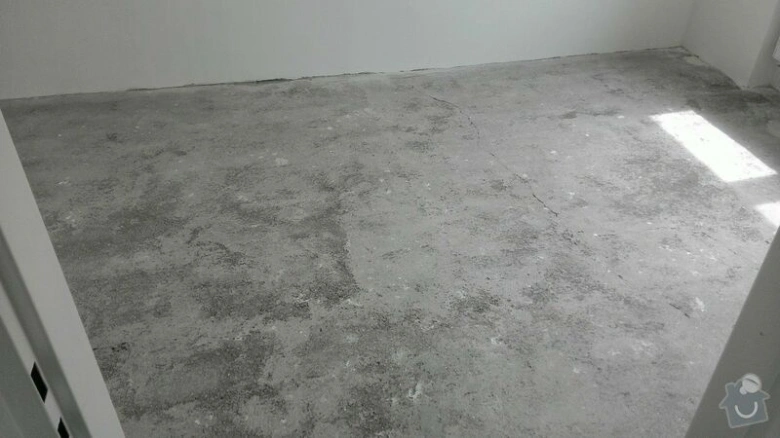 Neúpravená betonová podlaha v místnosti připravené na rekonstrukci.