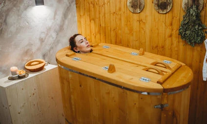 Muž v dřevěné lázni pro relaxaci.