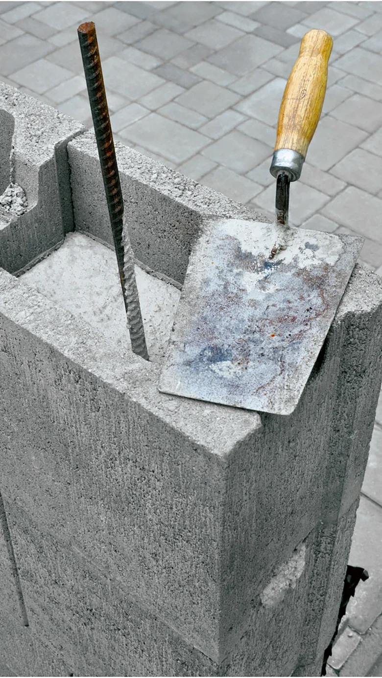 Betonový blok s výztuží a špachtlí na stavbě.