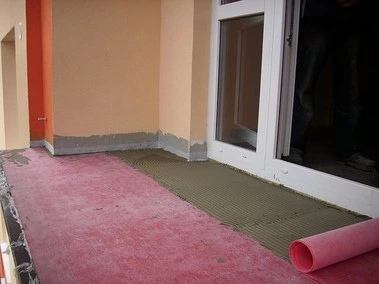Příprava podlahy na balkóně s izolační vrstvou před pokládkou dlažby.