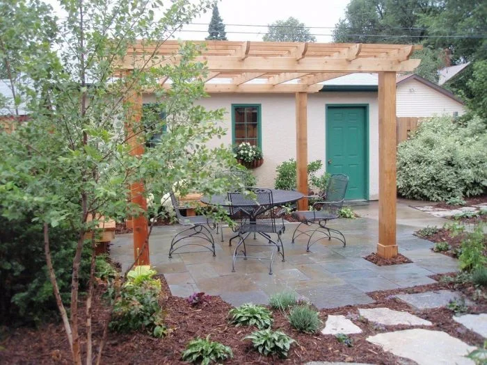 Dokončená dřevěná pergola nad zahradním posezením.