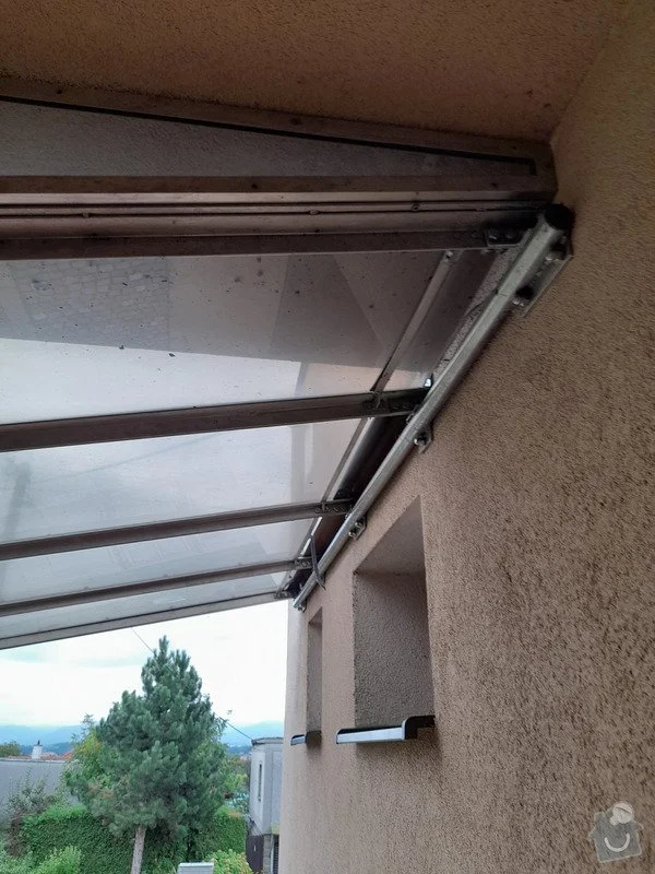 Detailní pohled na montáž stříšky nad dveře s kovovým nosičem.