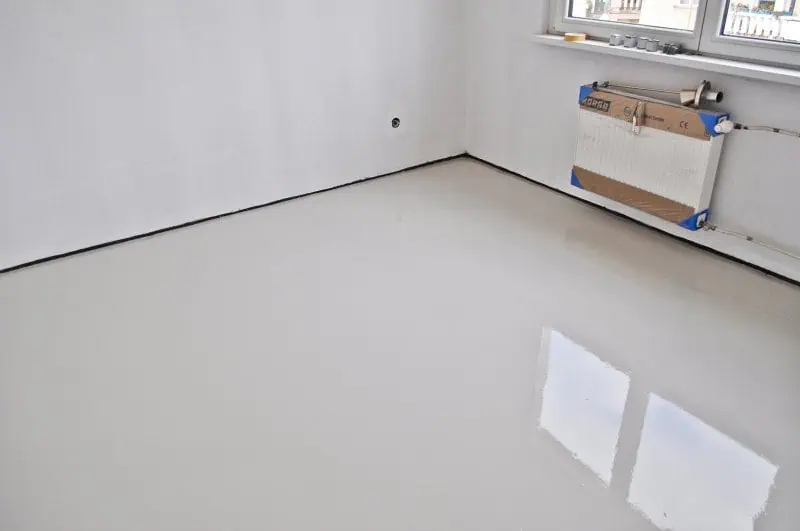 Bílá samonivelační stěrka na podlaze s lesklým povrchem.