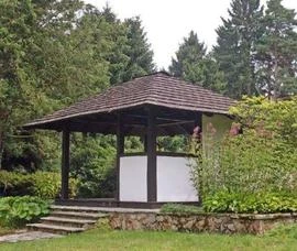 Dřevěná pavilónová střecha s taškami v přírodním prostředí.