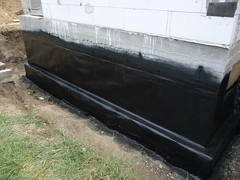 Černá hydroizolační vrstva na základové zdi budovy.