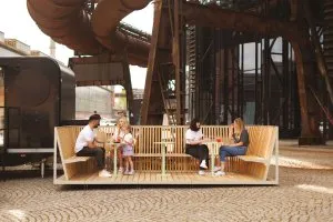 Lidé sedí na lavičce před ikonickou věží v ostravské architektuře.