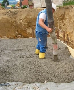 Stavebník nalévá beton do základové jámy na stavbě.