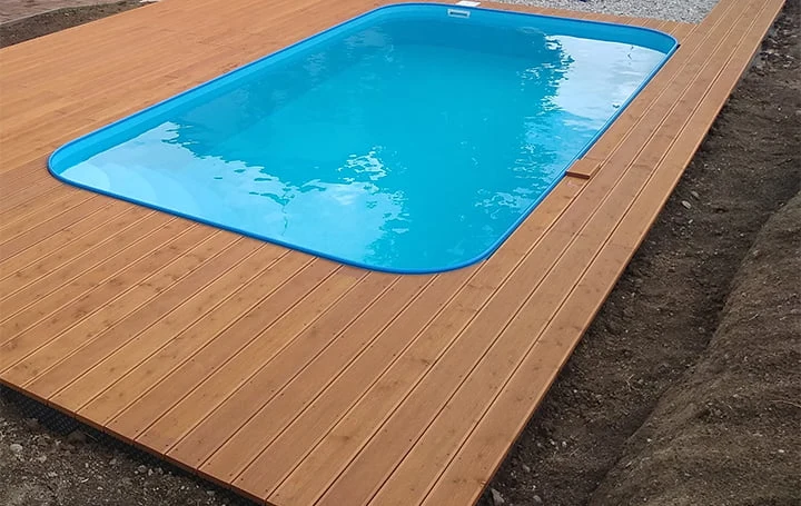 Nová dřevěná terasa kolem nadzemního bazénu na zahradě.