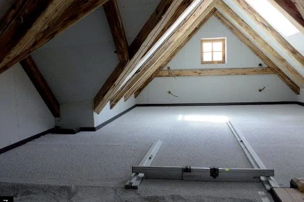 Neúplná podkroví s dřevěnými trámy a izolací na stropu.
