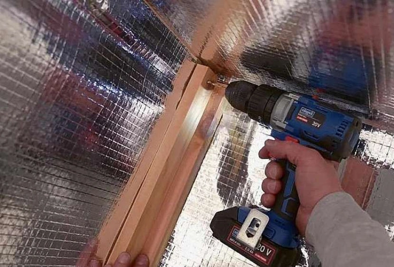 Montáž dřevěného rámu do izolace při stavbě malého domu.