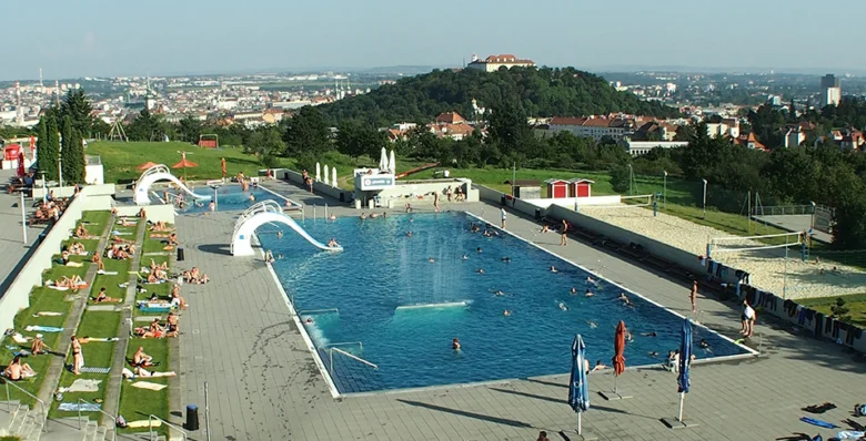 Venkovní bazén na kopci s tobogány a soláři.