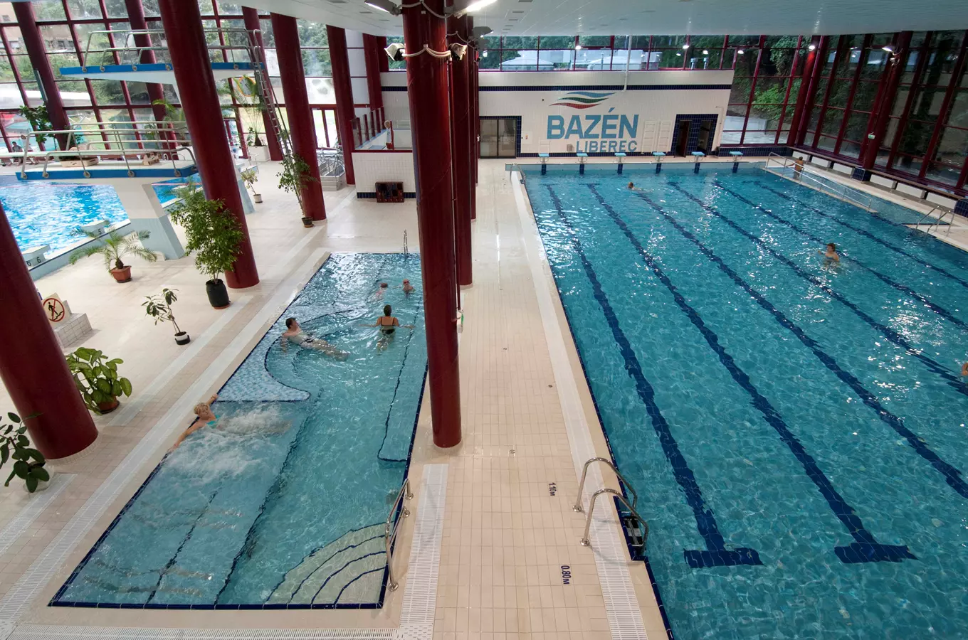 Vnitřní plavecký bazén v Liberci s více bazény a koupajícími se lidmi.