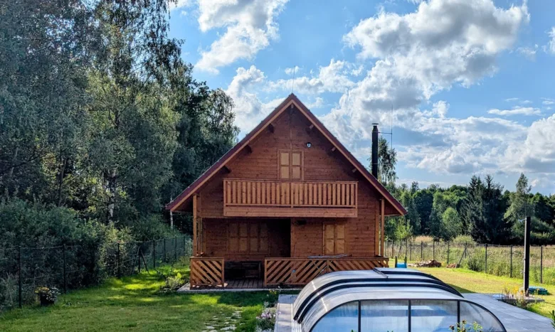 Dřevěná chata pro celoroční bydlení uprostřed zelené zahrady.