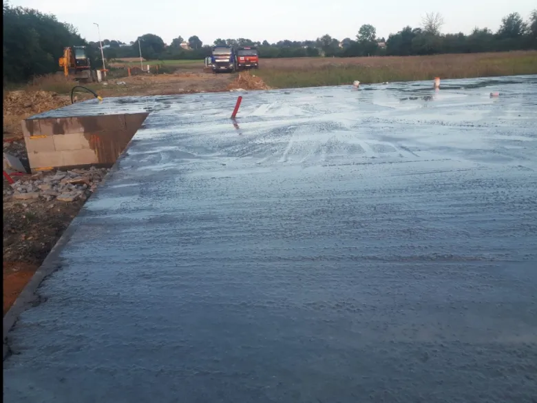 Čerstvě nalitý betonový základ s viditelným bedněním na staveništi.