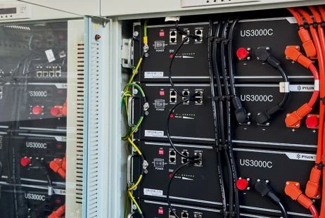 Černé baterie pro úložiště energie v skříni s oranžovými kabely.