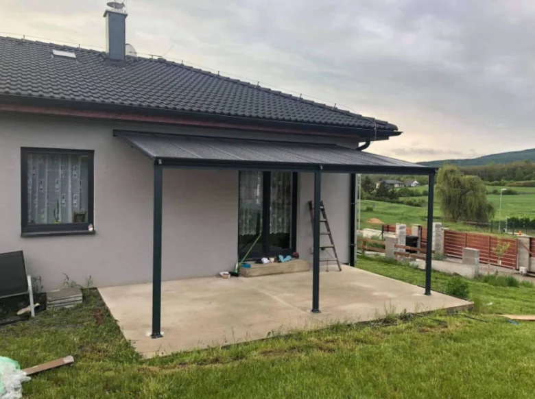 Nová hliníková pergola na terase domu s betonovou podlahou.
