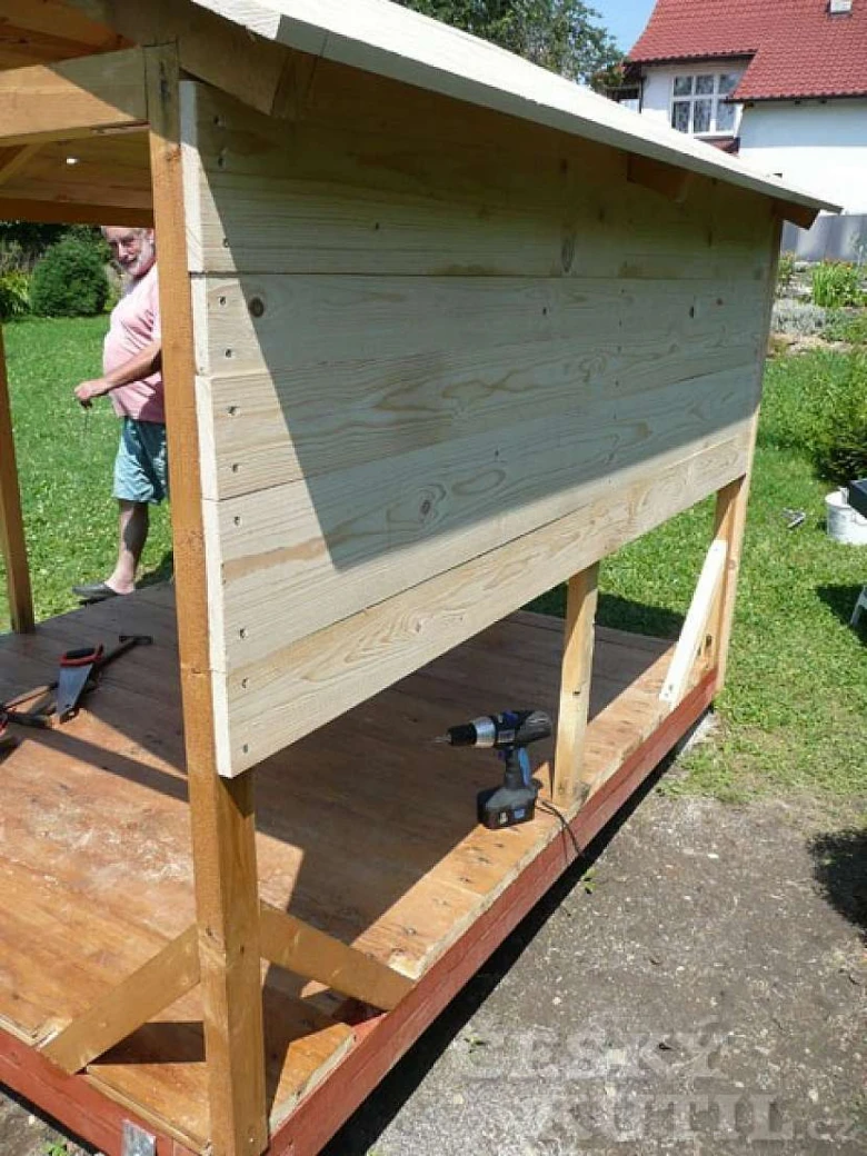 Stavba dřevěného dětského domečku v zahradě s nářadím.
