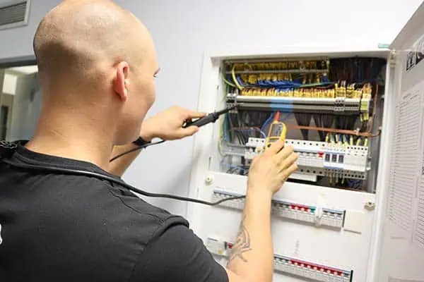 Elektrikář testuje jistič v rozvaděči multimetrem.
