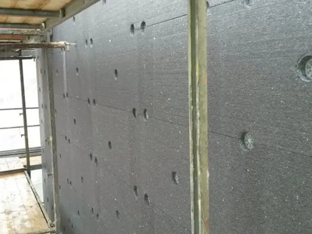 Šedé panely grafitového styroporu na fasádě budovy během stavebních prací.