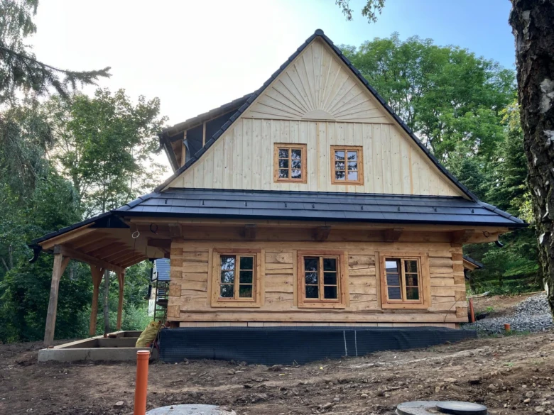 Dřevěná roubená stavba v přírodě během výstavby.