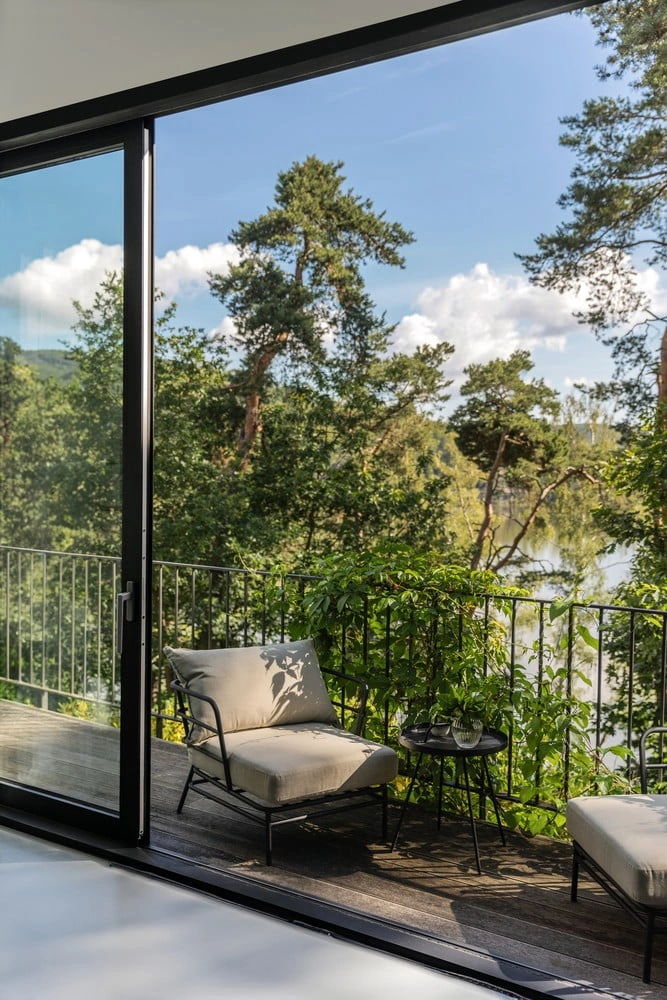 Moderní balkon s dřevěnou podlahou a výhledem do přírody.