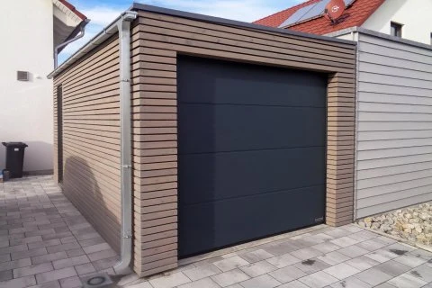 Moderní garáž s tmavými dveřmi pro jedno auto.
