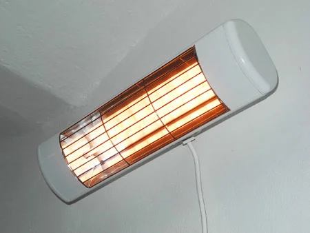 Bílý elektrický infra přímotop namontovaný na stěně v interiéru.