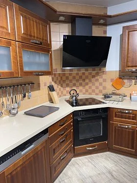 Moderní kuchyň s dřevěnými skříněmi a ocelovými spotřebiči.