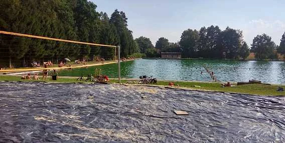 Venkovní bazén v Jeseníkách s lidmi na břehu mezi stromy.