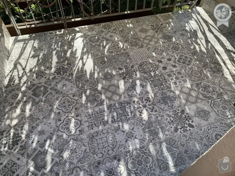 Nově dlažděný balkon s ornamentálními bílými a černými mozaikami.