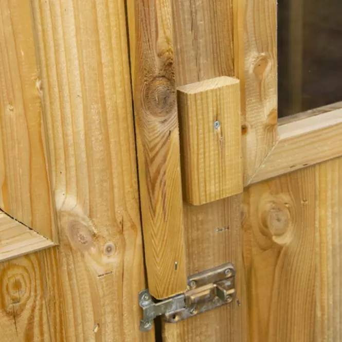Detail kovového západky na dřevěných dveřích pro zahradní nástrojovou skříň.