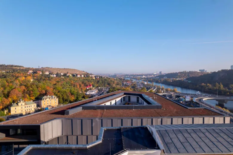 Moderní střechy Barrandovských teras s výhledem na řeku a les.