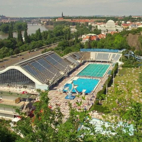 Venkovní plavecký bazén s více dráhami a výhledem na Prahu