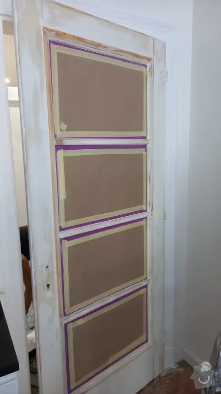 Bílá dveře s maskovací páskou při malování v interiéru.