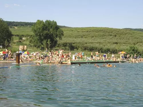 Přírodní koupaliště na jižní Moravě s lidmi v bazénu.