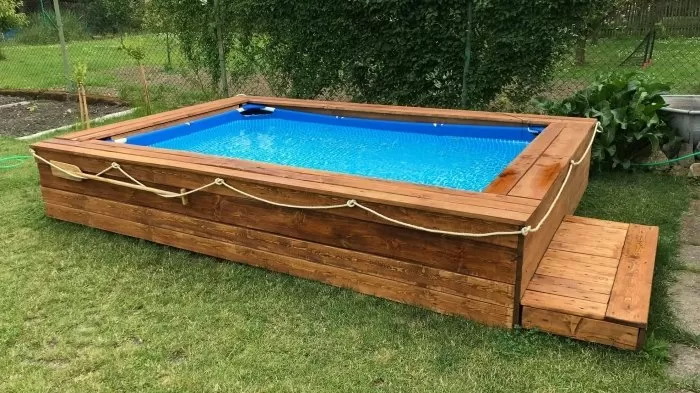 Dřevěné obložení nadzemního bazénu na trávníku.