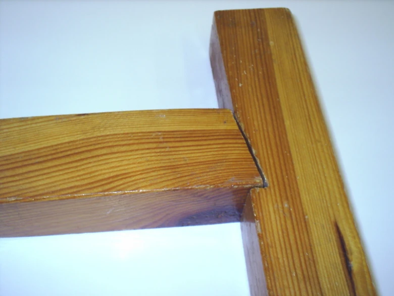Detailní pohled na tesané spojení dvou dřevěných trámů v konstrukci.
