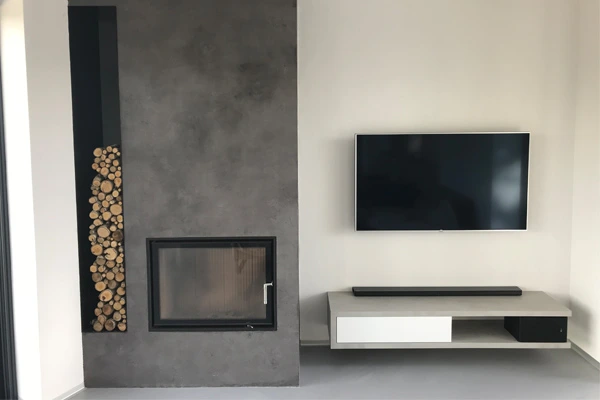 Moderní interiér s betonovou stěrkou na krbu u televize.