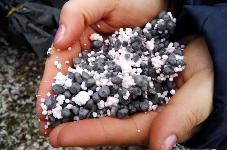 Ruce drží směs černých granulí expandovaného polystyrénu s bílými částicemi