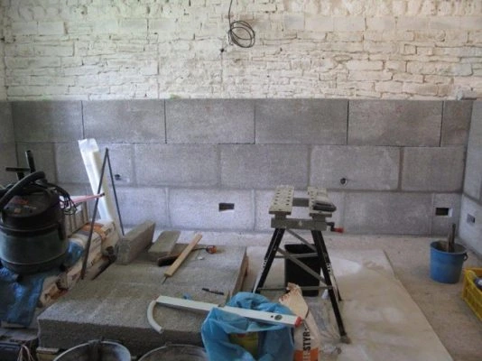 Stavba podkladu domu z betonových bloků s nástroji a materiály.