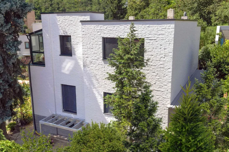 Bílá omítaná fasáda s větranou konstrukcí na moderním domě.
